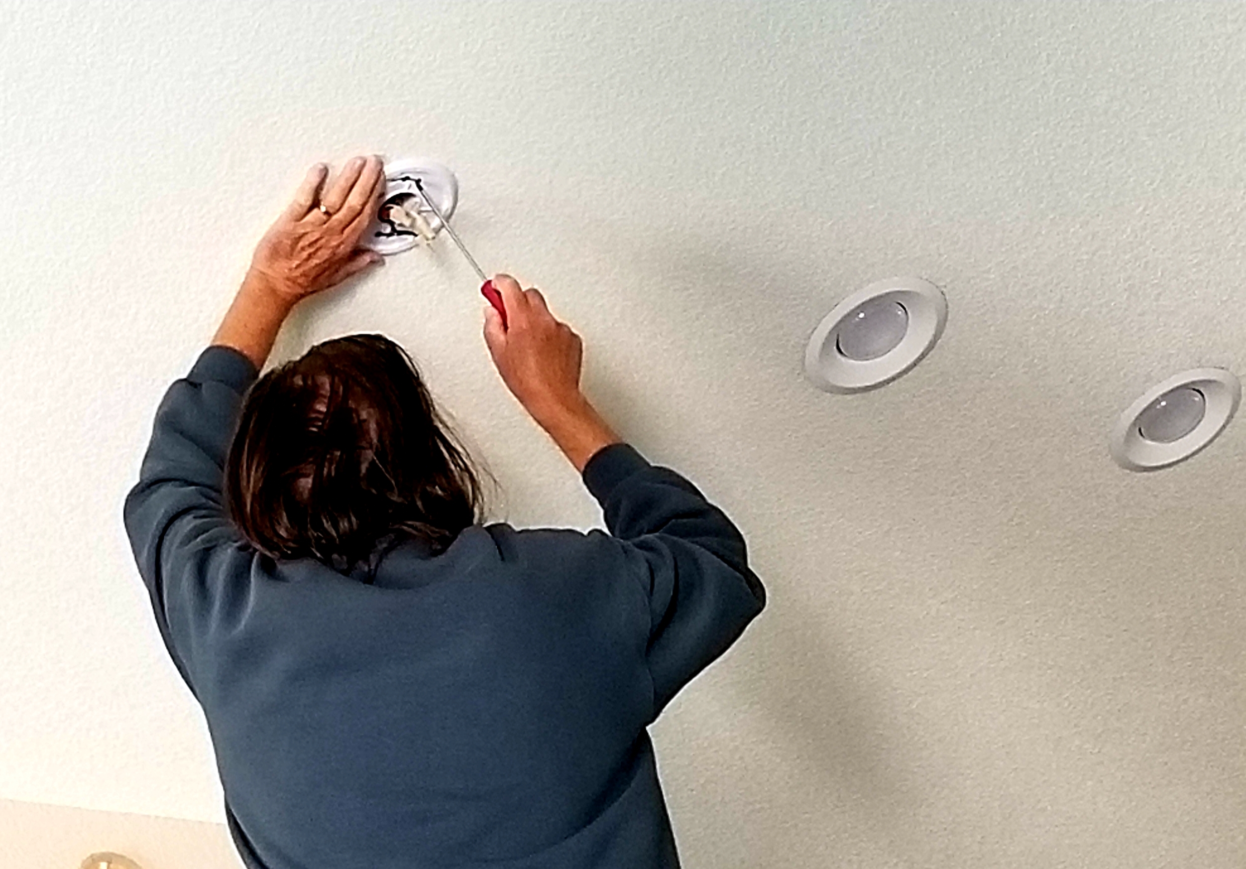 Homeowner Attempting To Replace Smoke Alarm On Ceiling